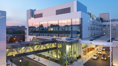 Exterior glass front of multi-story hospital with covered walkway between buildings